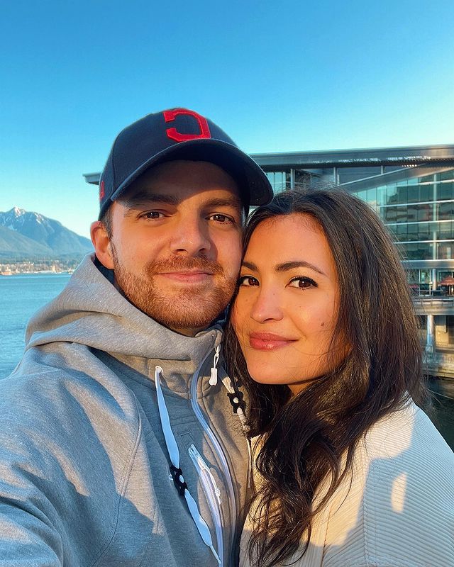 Jenna Romanin is wearing a white sweater with her boyfriend, who is wearing a cap and hoodie